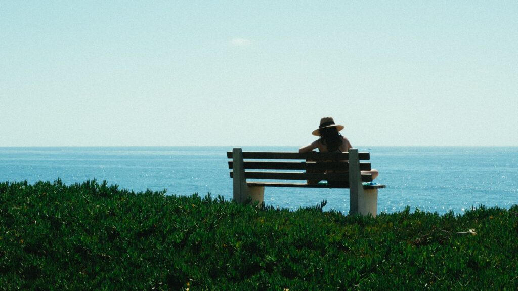 Solo-traveler on a bench in front of the ocean